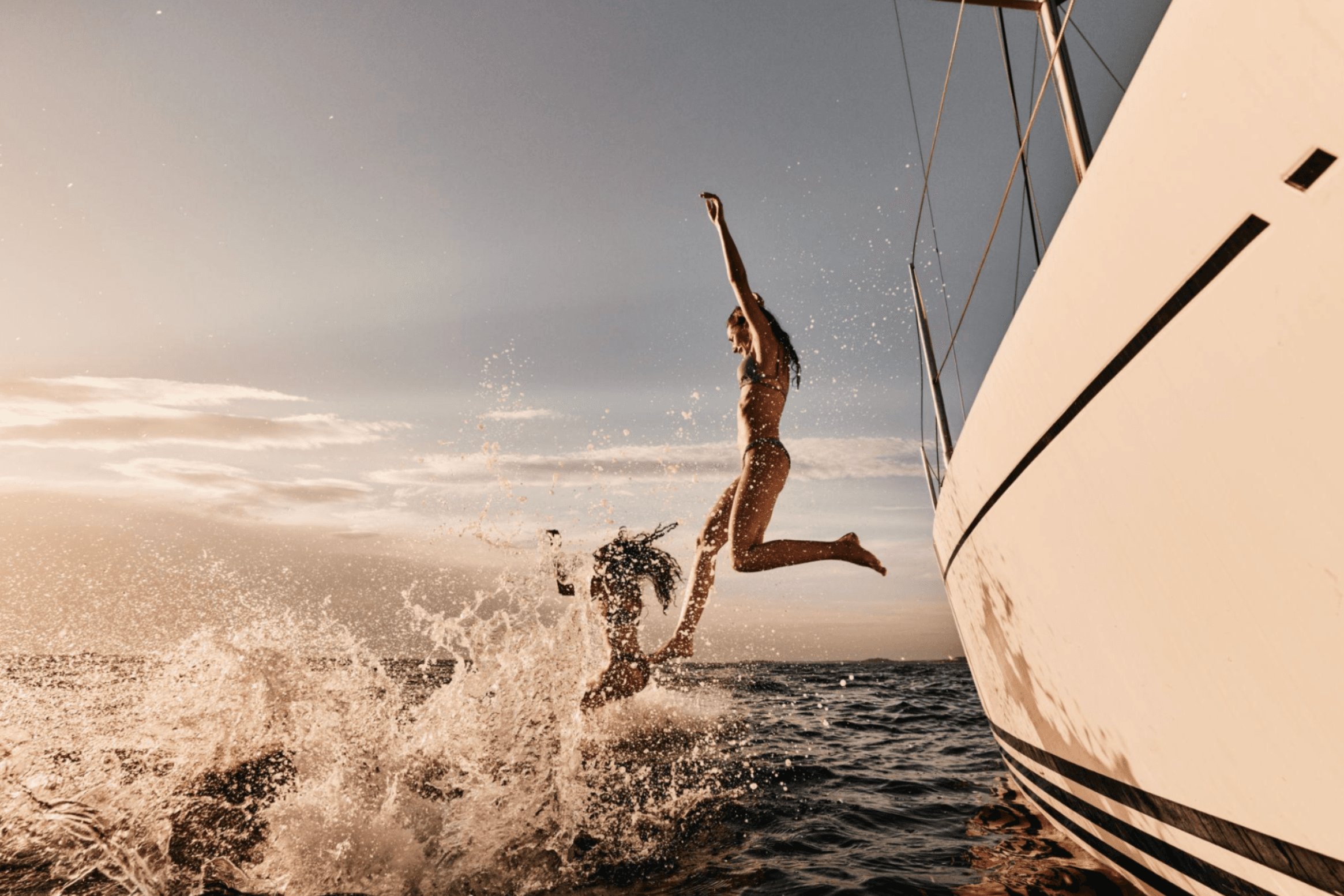 Women jumping from a sailboat into the ocean